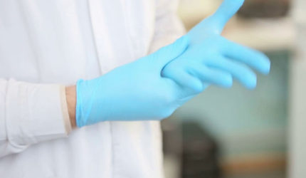 Close up of blue latex gloves being put on